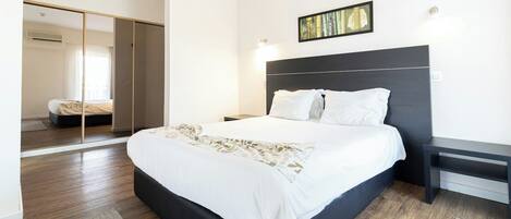 Un dormitorio moderno con una cama grande, un cabecero oscuro y una mesita de noche.