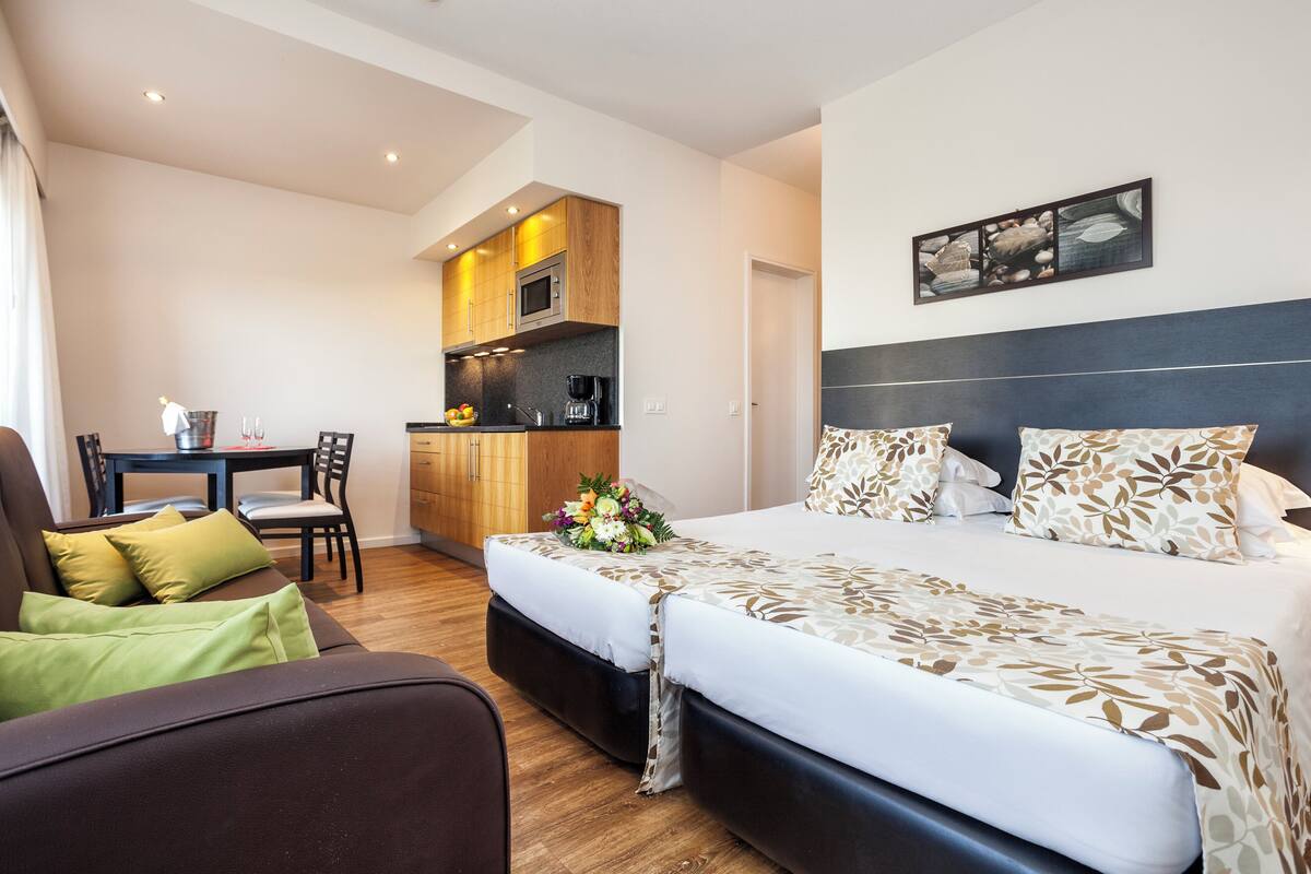 Une chambre d’hôtel comprenant un lit, un canapé, une table à manger et un coin cuisine.