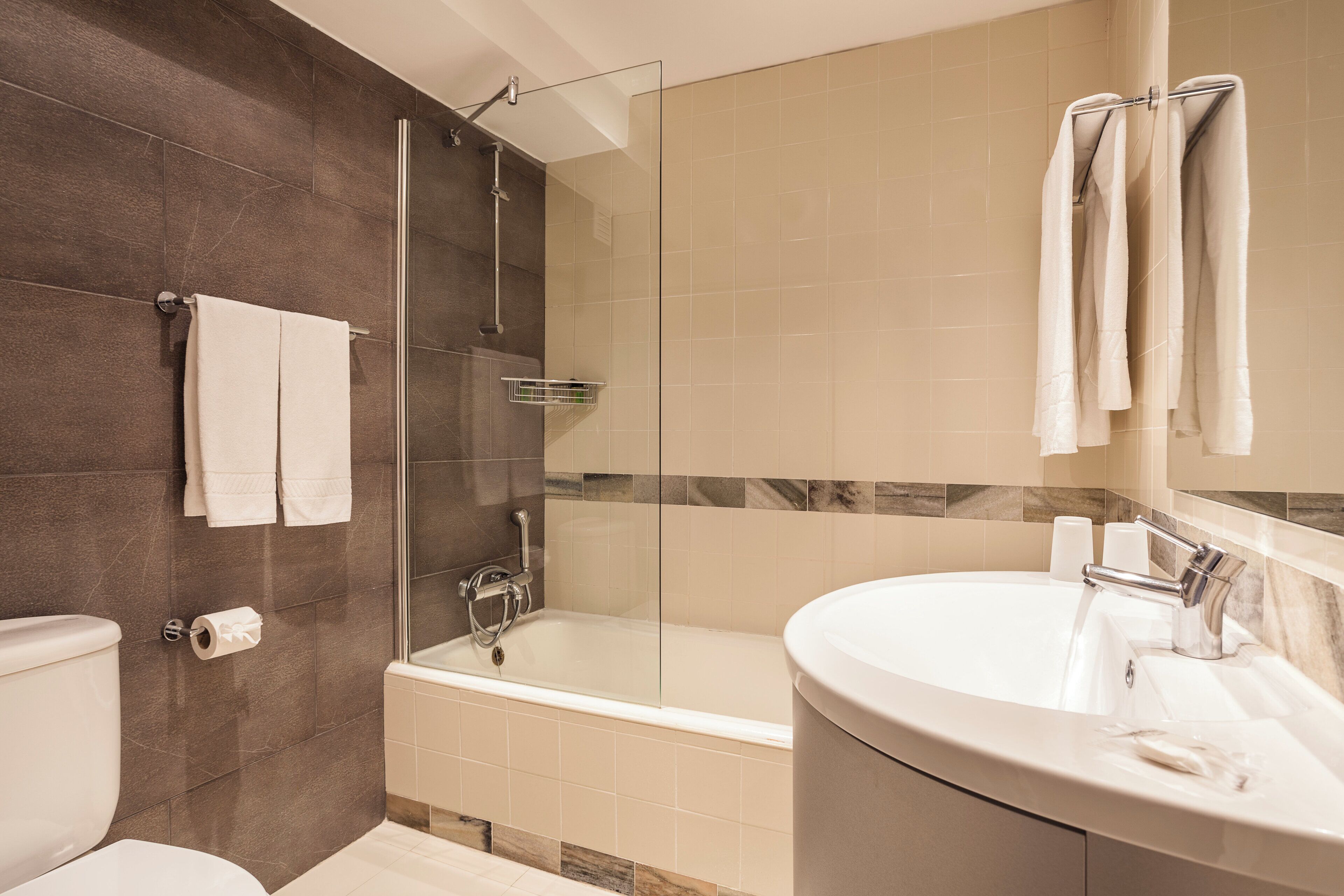 Un bagno moderno con doccia vetro, vasca freestanding e lavabo su mobile.