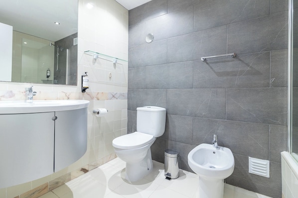 A modern bathroom with a toilet, bidet, and sink.