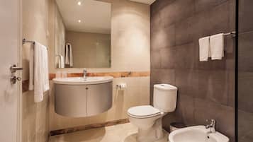 Un baño moderno con inodoro, bidé, lavamanos y espejo.