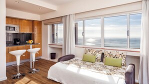 A modern hotel room with a large bed, a kitchenette, and a view of the sea. - Alvor Atlântico Residences (Portimão)