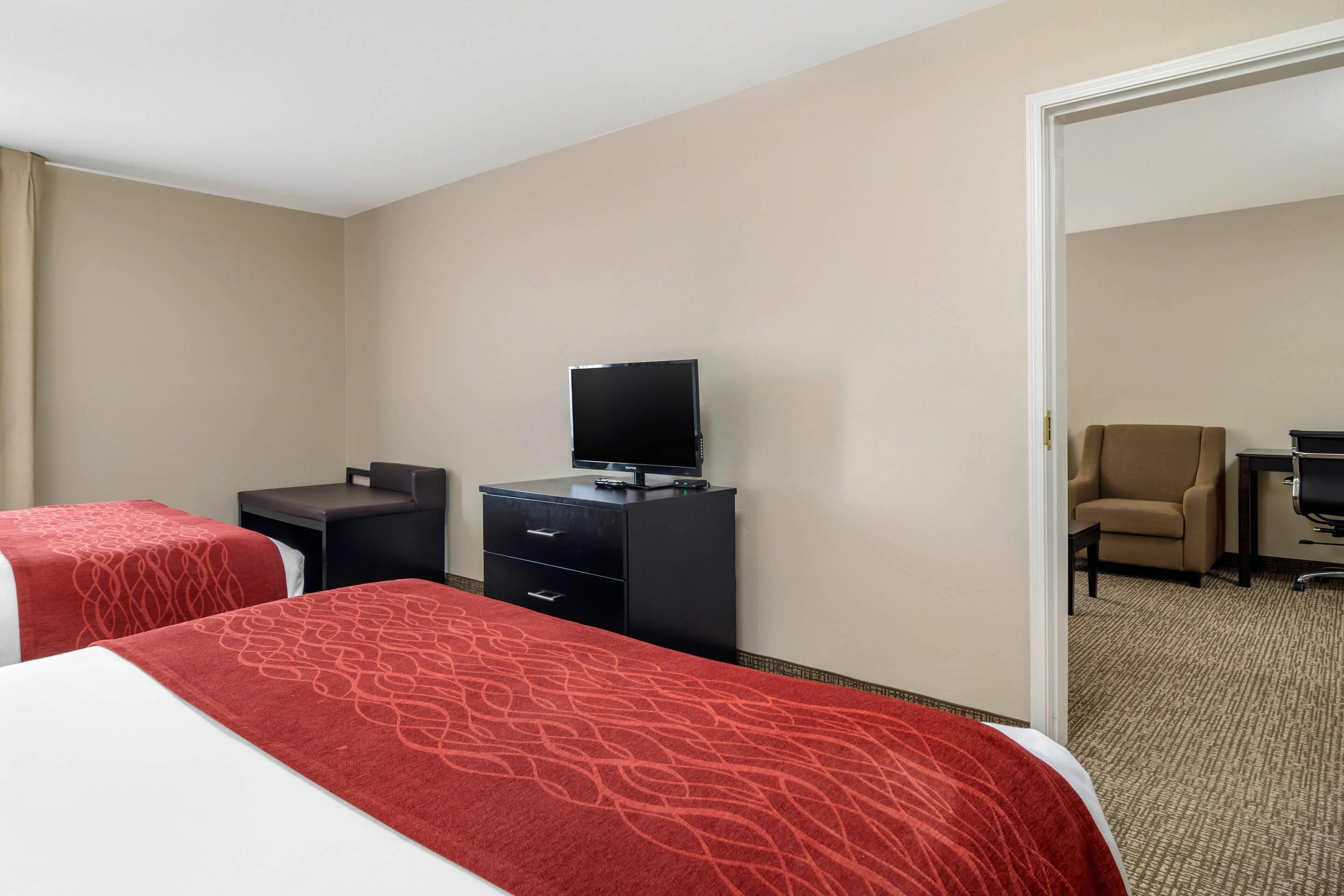 Une chambre d’hôtel avec deux lits, un bureau avec une télévision et une chaise.