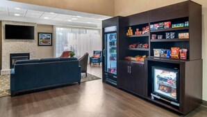 A hotel lobby with a seating area, a refrigerator stocked with snacks, and a television mounted on the wall. - Comfort Inn & Suites Atlanta/Smyrna (Smyrna)