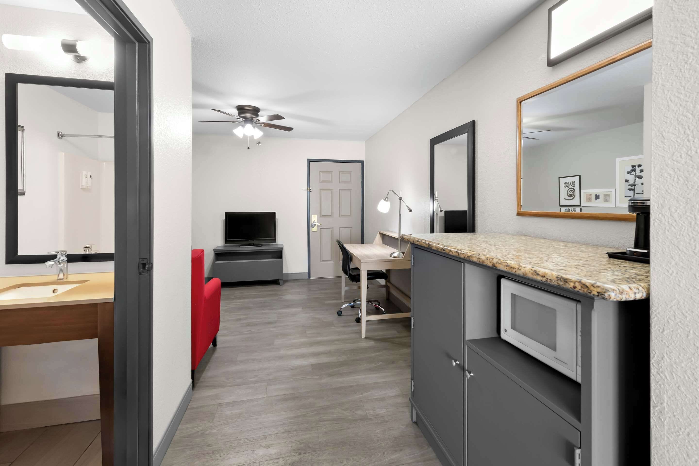 Un baño moderno con tocador, espejo y ventilador de techo.