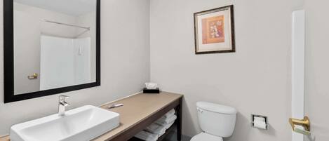 A bathroom with a white sink, a toilet, a framed picture on the wall, and a towel rack.