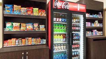 Una máquina expendedora llena de bocadillos y un refrigerador Coca-Cola con diversas bebidas.