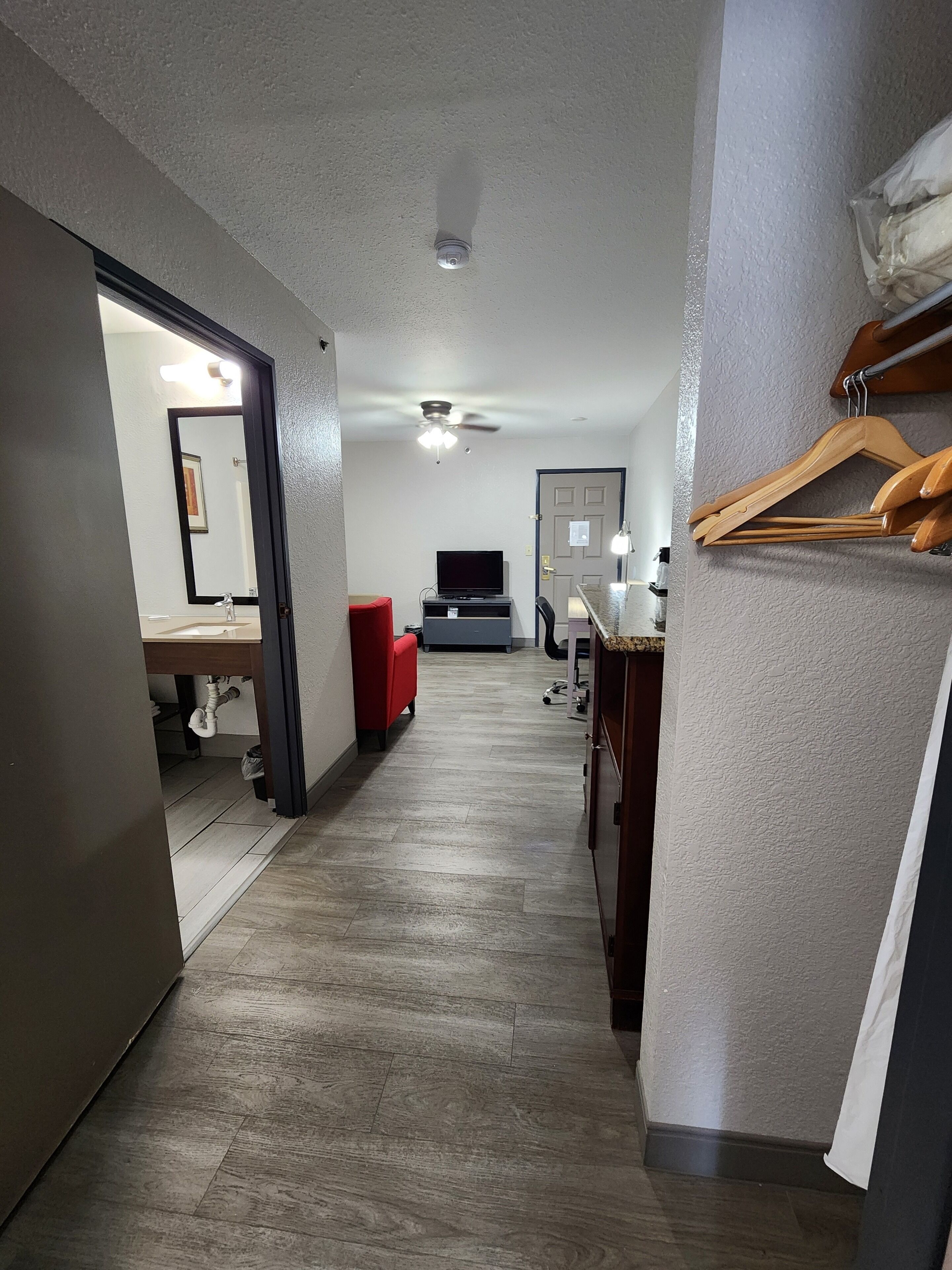 A hallway with a ceiling fan, a TV, and a red chair.