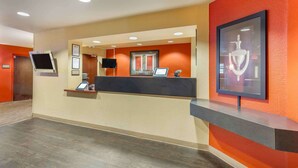 A reception area with a counter, a mounted television, framed certificates, and a framed trophy on the wall. - Extended Stay America Suites Temecula Wine Country (Temecula)
