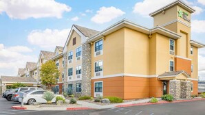 A multi-story hotel with a yellow facade, stone accents, and a parking lot with several cars. - Extended Stay America Suites Temecula Wine Country (Temecula)