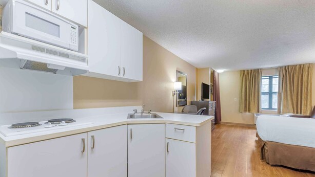 A compact hotel room with a kitchenette, a bed, a desk, and a window with curtains. - Extended Stay America Suites Temecula Wine Country (Temecula)