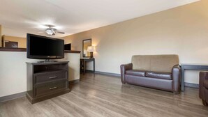 A living room with a flat-screen TV, a ceiling fan, a sofa, and a lamp. - Extended Stay America Select Suites - Austin - Northwest - Lakeline Mall (Austin)