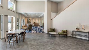 Un hall d’hôtel spacieux avec un grand espace de restauration, un escalier et une vue sur une partie de la cuisine.