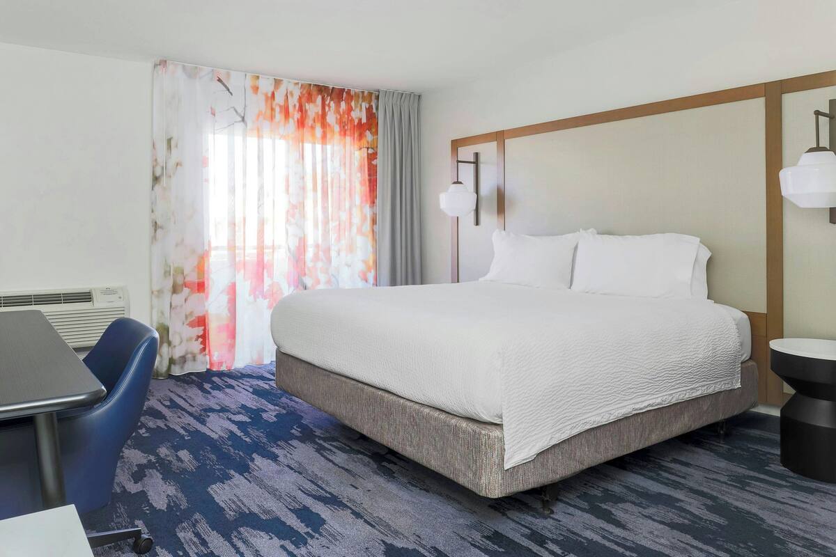 Una habitación de hotel con una cama grande, un escritorio y una silla.