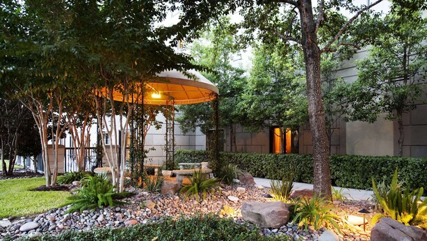 Un jardin aménagé avec un belvédère, des arbres et une variété de plantes.