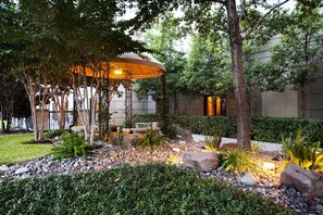 Un jardin aménagé avec un belvédère, des arbres et une variété de plantes.