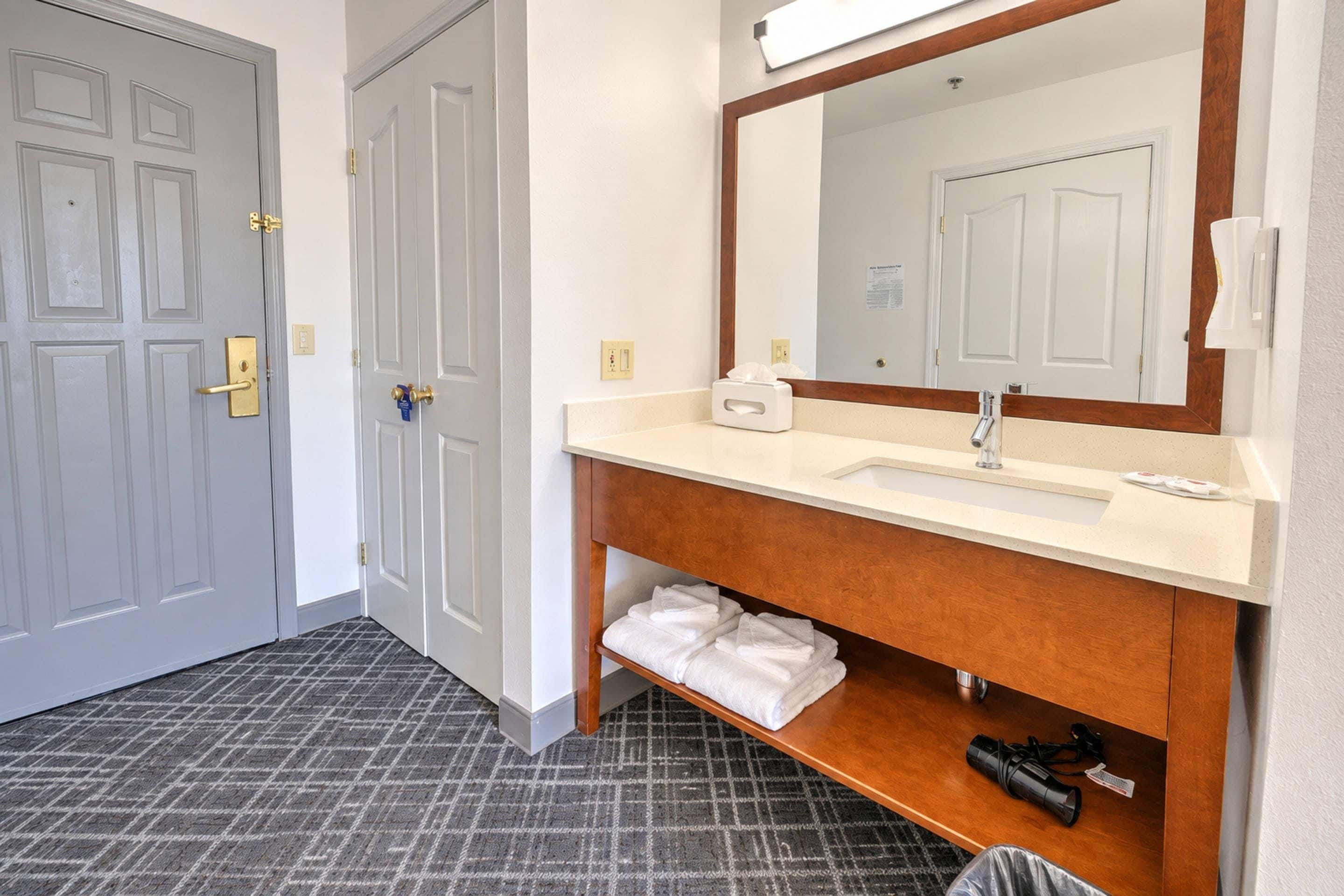 A hotel bathroom with a white sink, a mirror, and a towel rack.