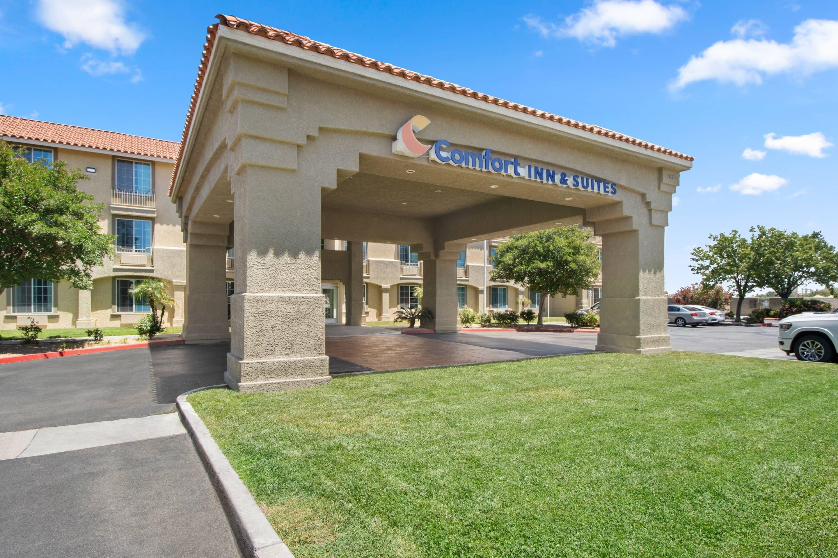 Edificio de Comfort Inn & Suites con entrada cubierta, estacionamiento y césped bien cuidado.
