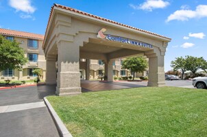 Edificio de Comfort Inn & Suites con entrada cubierta, estacionamiento y césped bien cuidado.