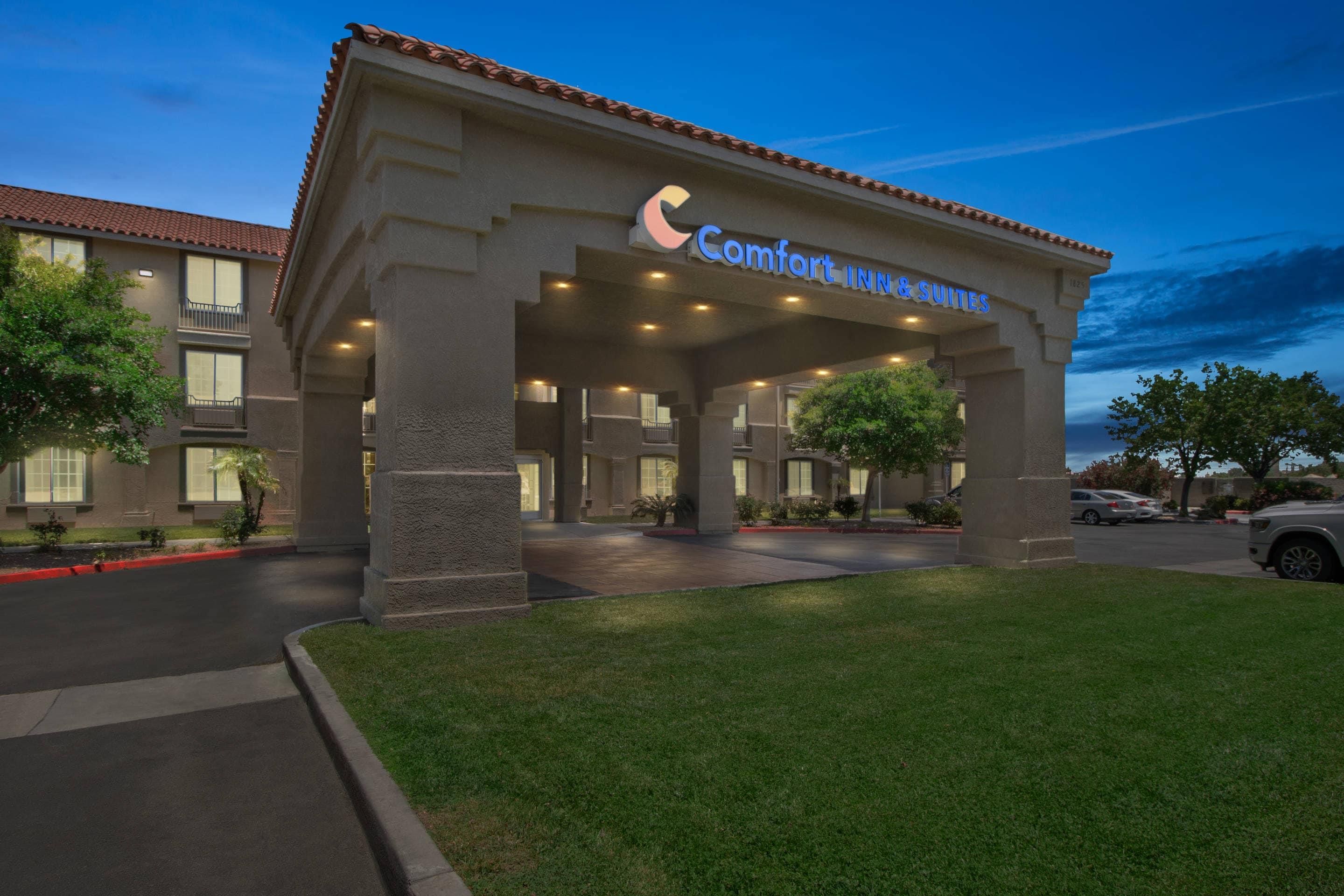 A hotel entrance with a covered area, a sign for Comfort Inn & Suites, and a parking lot.