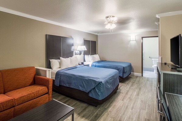 A hotel room with two beds, a sofa, a desk, a TV, and a ceiling fan. - Econo Lodge Inn & Suites Corpus Christi (Corpus Christi)