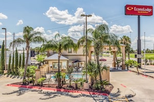 Een hotel met een zwembad, palmbomen en een bord met EconoLodge Inn & Suites.