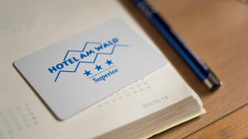 A hotel card labeled "HOTEL AM WALD" with a star rating of "Superior" and a calendar page indicating "Woche 14".