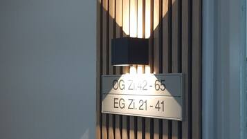 A wall with vertical wooden slats and a sign indicating room numbers.