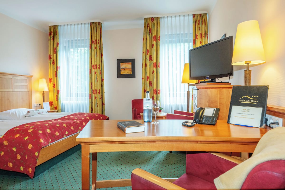 A hotel room with two beds, a desk with a computer, a telephone, and a television.