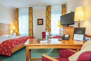 Habitación de hotel con dos camas, un escritorio con computadora, teléfono y televisión.