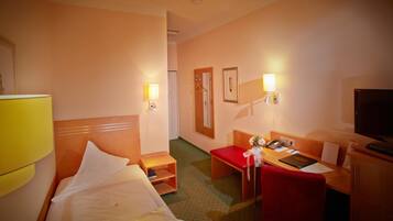 Une chambre d’hôtel équipée d’un lit, d’un bureau, d’une chaise, d’une télévision et d’un miroir.