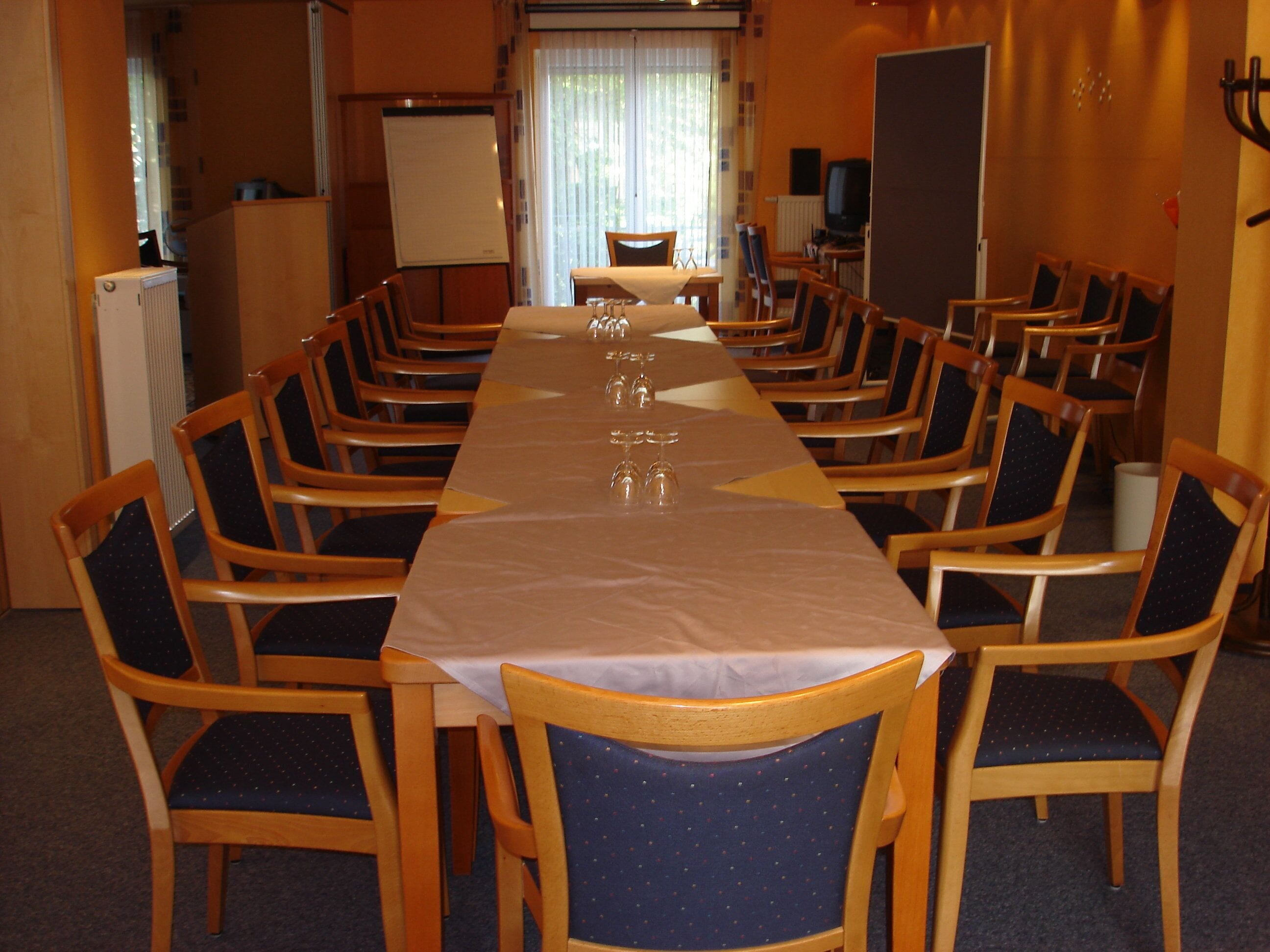 Ein Konferenzraum mit einem langen Tisch und mehreren Stühlen.