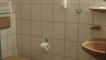 A bathroom with a toilet, sink, and mirror.