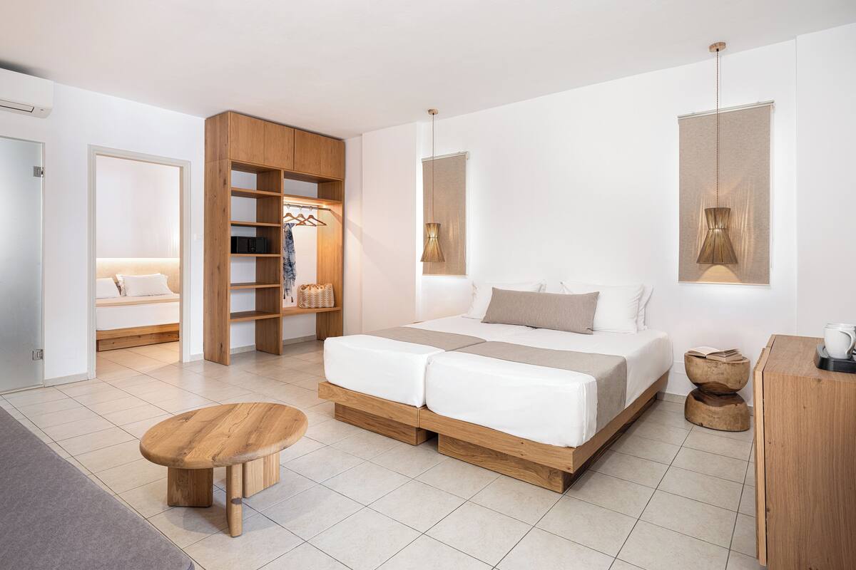 Un dormitorio moderno con una cama de madera, un armario empotrado y una pequeña mesa de madera.