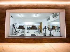 Un gimnasio con equipo de ejercicio, un espejo grande y suelo de madera.