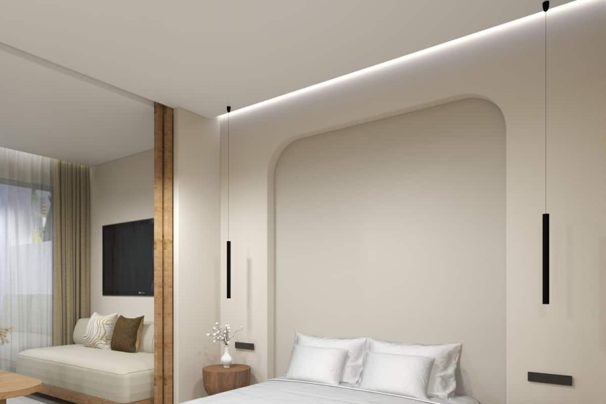 Un dormitorio moderno con una cama grande, un sofá, una mesita de madera redonda y un espejo.