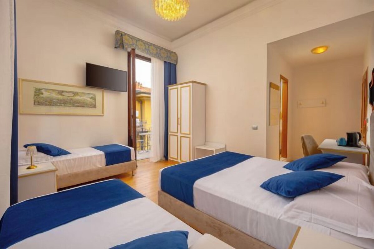 A hotel room with two beds, a TV, a wardrobe, and a balcony with a view.