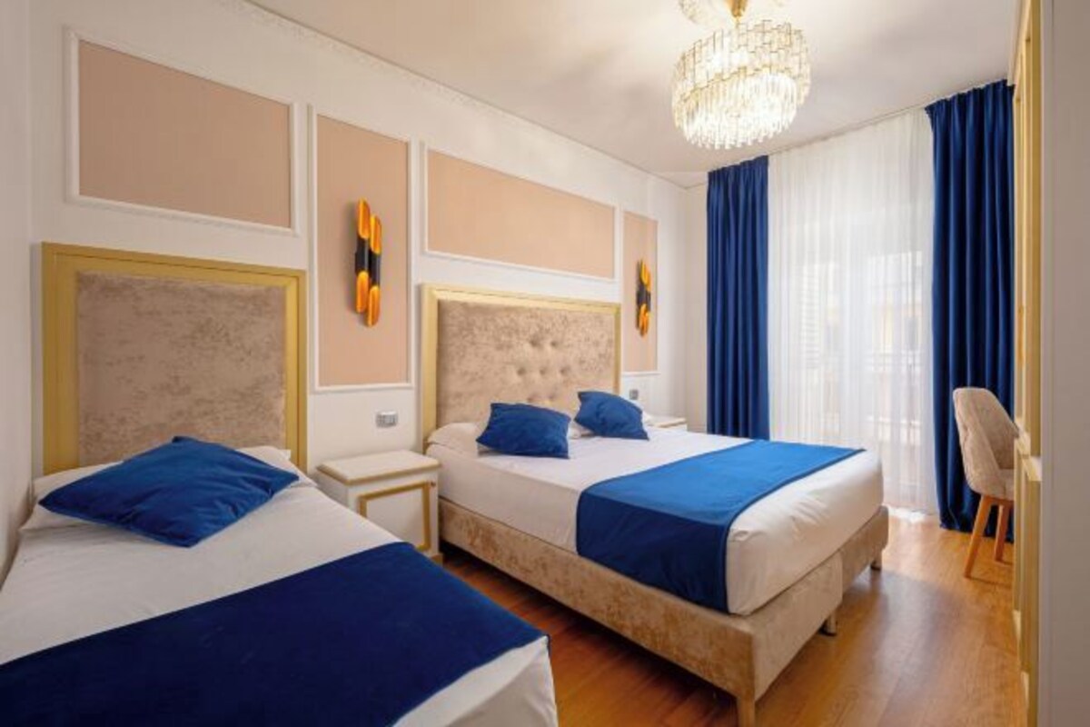 Habitación de hotel con dos camas, un candelabro y vistas a la ciudad.