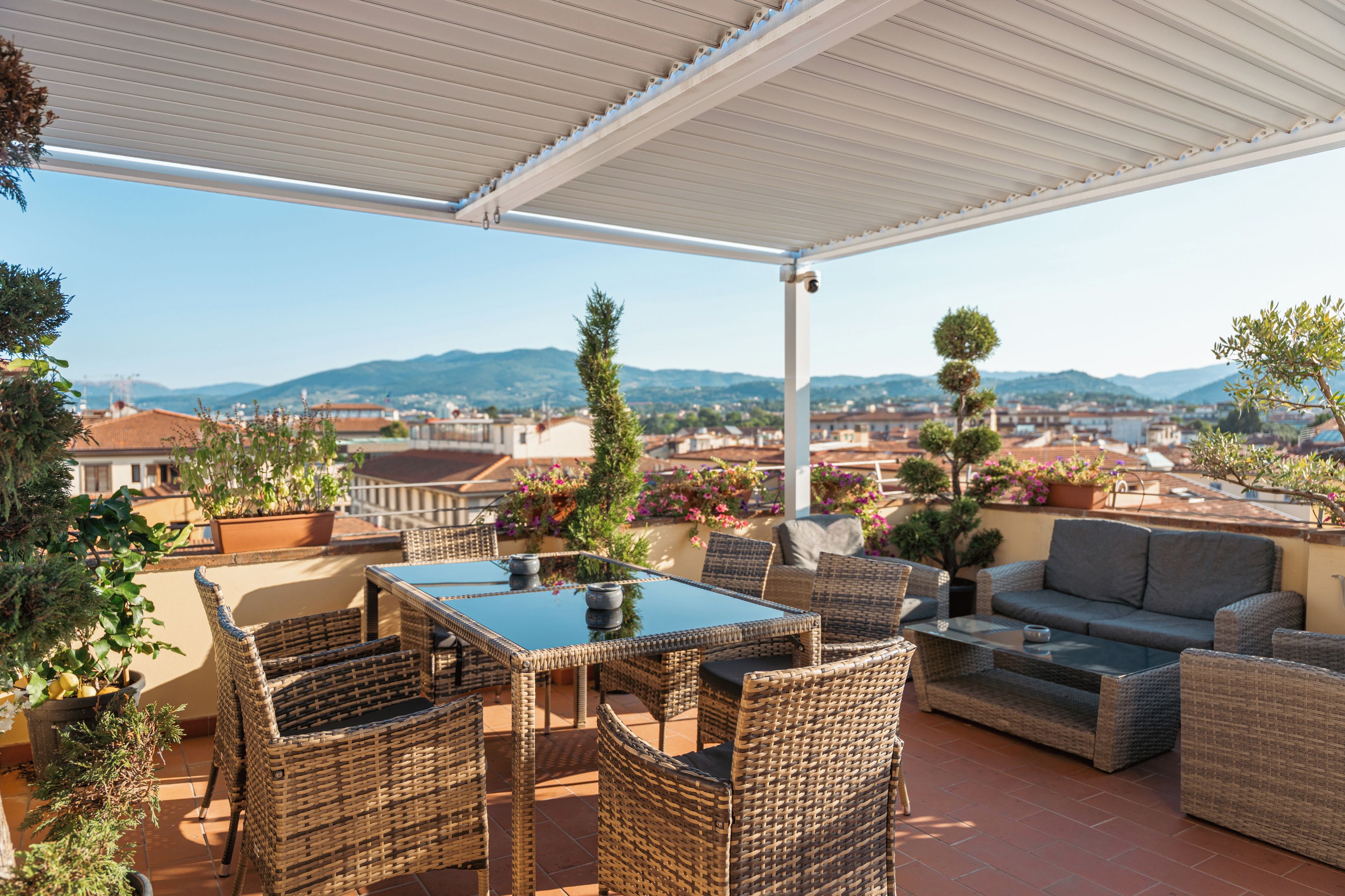 Un espacio de estar al aire libre techado con muebles de mimbre y vistas a la ciudad.