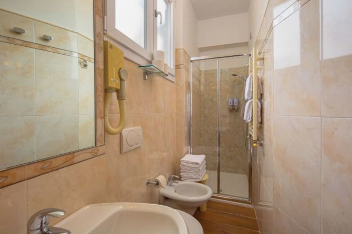 Un baño con bañera, inodoro y zona de ducha con mampara de vidrio.