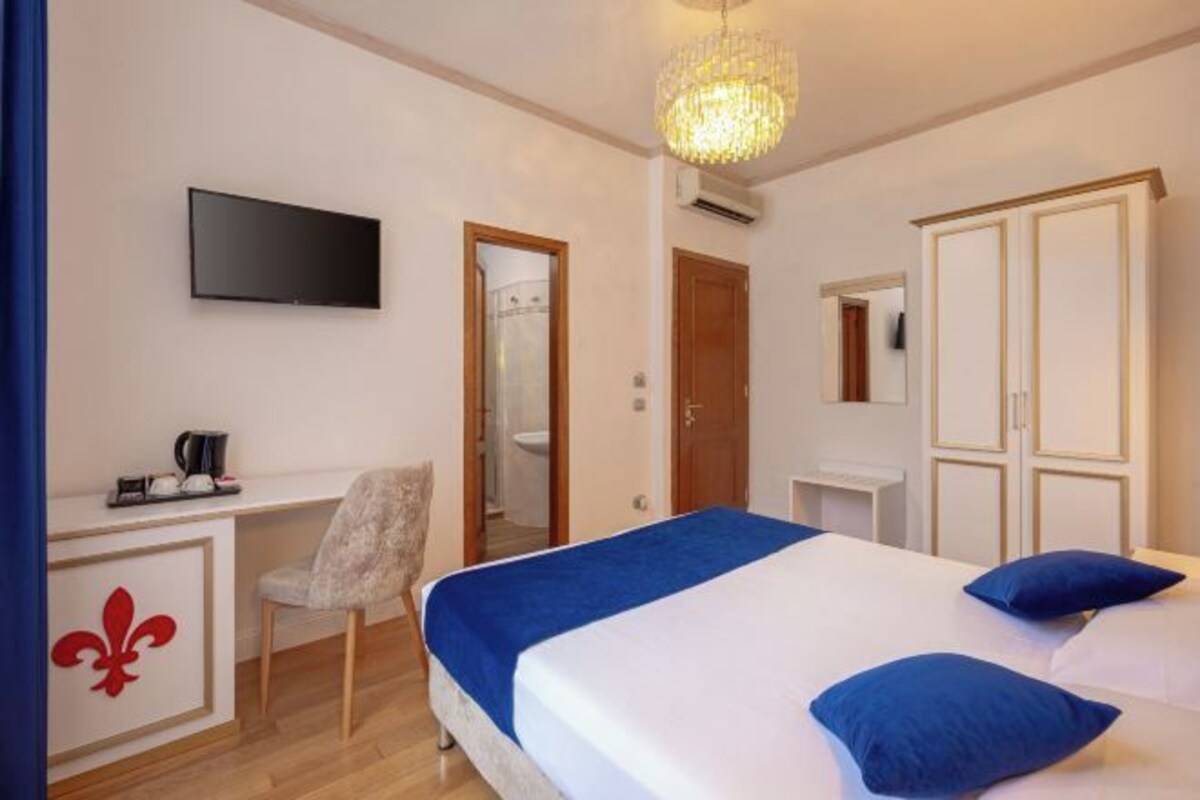 Una habitación de hotel con cama, escritorio, silla, televisor y armario.