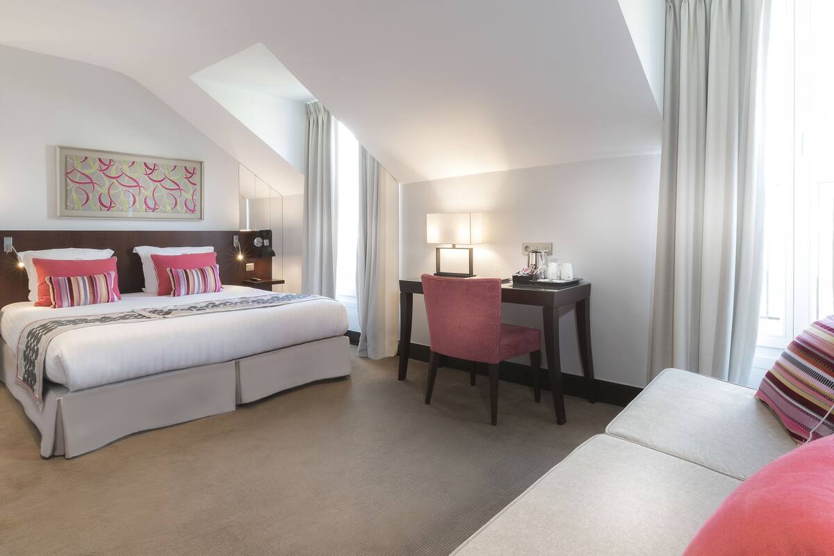 Une chambre d’hôtel avec un lit, un bureau, une chaise et un canapé.