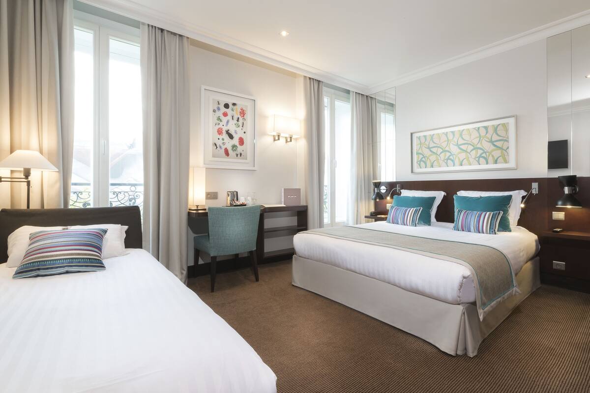 Une chambre d’hôtel avec deux lits, un bureau et une chaise.
