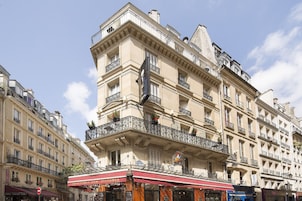 Un edificio a più piani con un balcone sporgente, il cartello di un ristorante e una vetrina ben visibile.