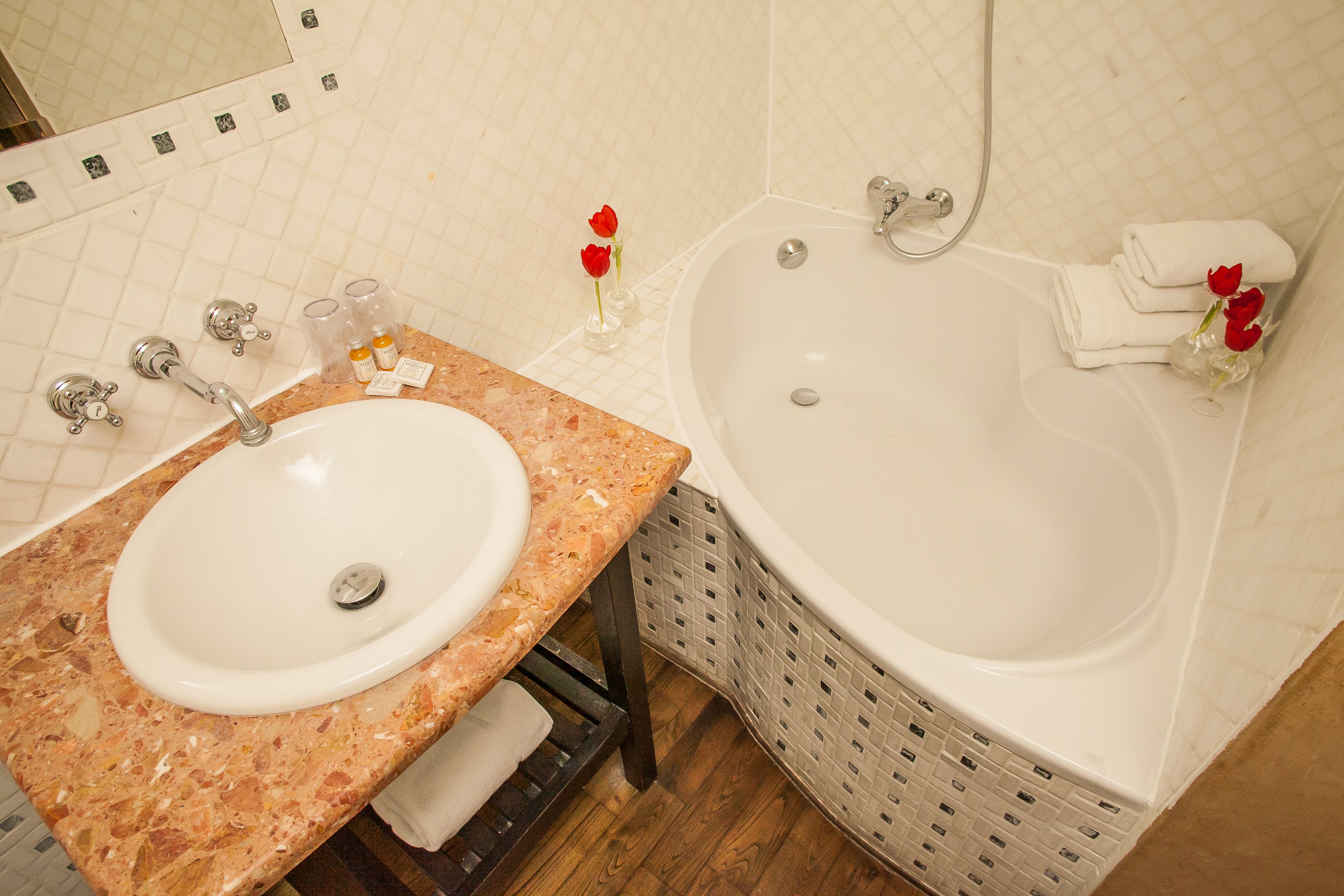 A bathroom with a marble sink, a bathtub, and a mirror.