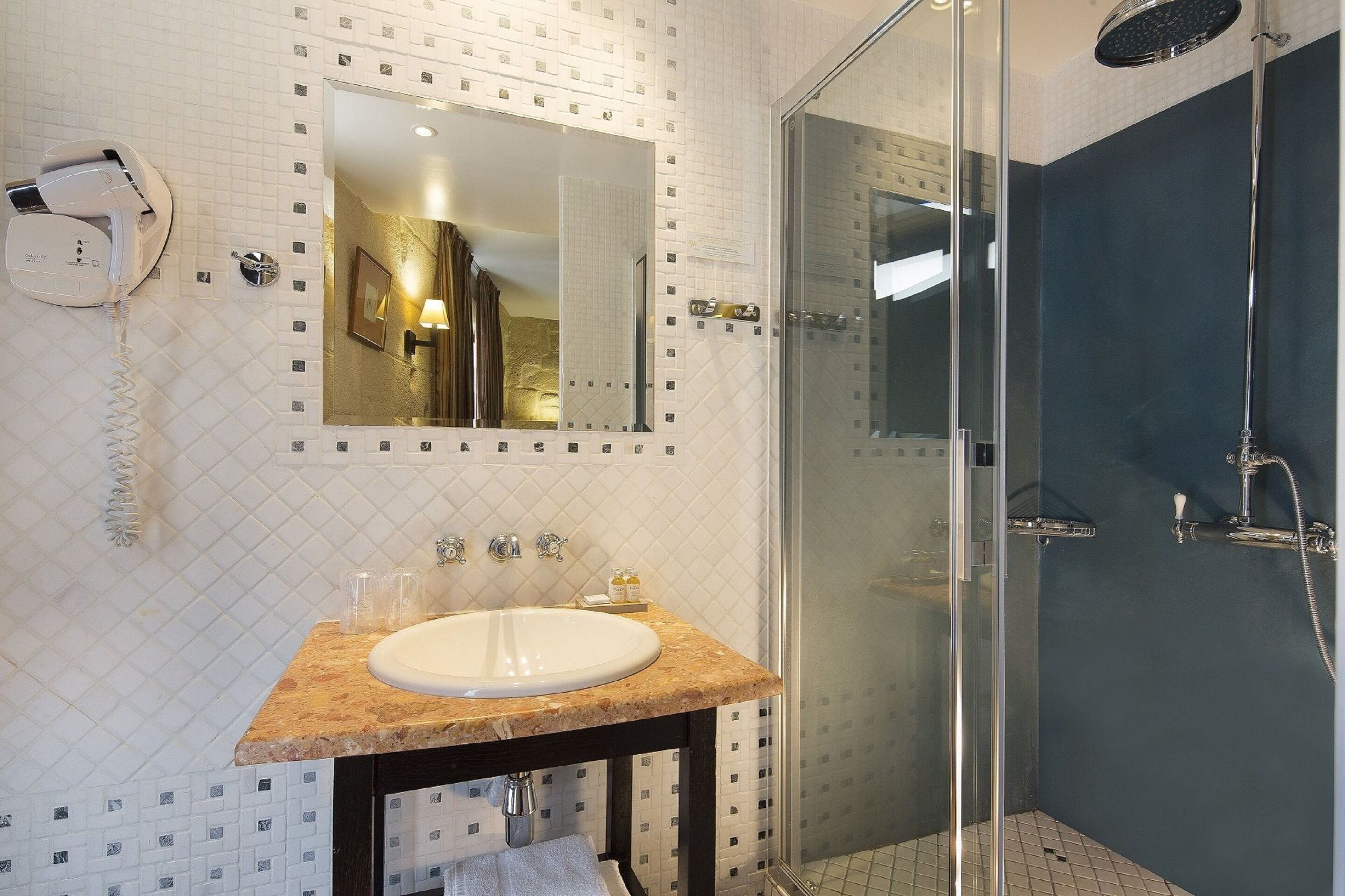 A modern bathroom with a glass-enclosed shower, a large mirror, and a marble sink.