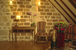 Una camera accogliente con un tavolo in legno, due lampade, una sedia, un vaso con fiori e una bottiglia.