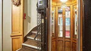 A wooden staircase with a metal handrail leading to a door with a glass panel.