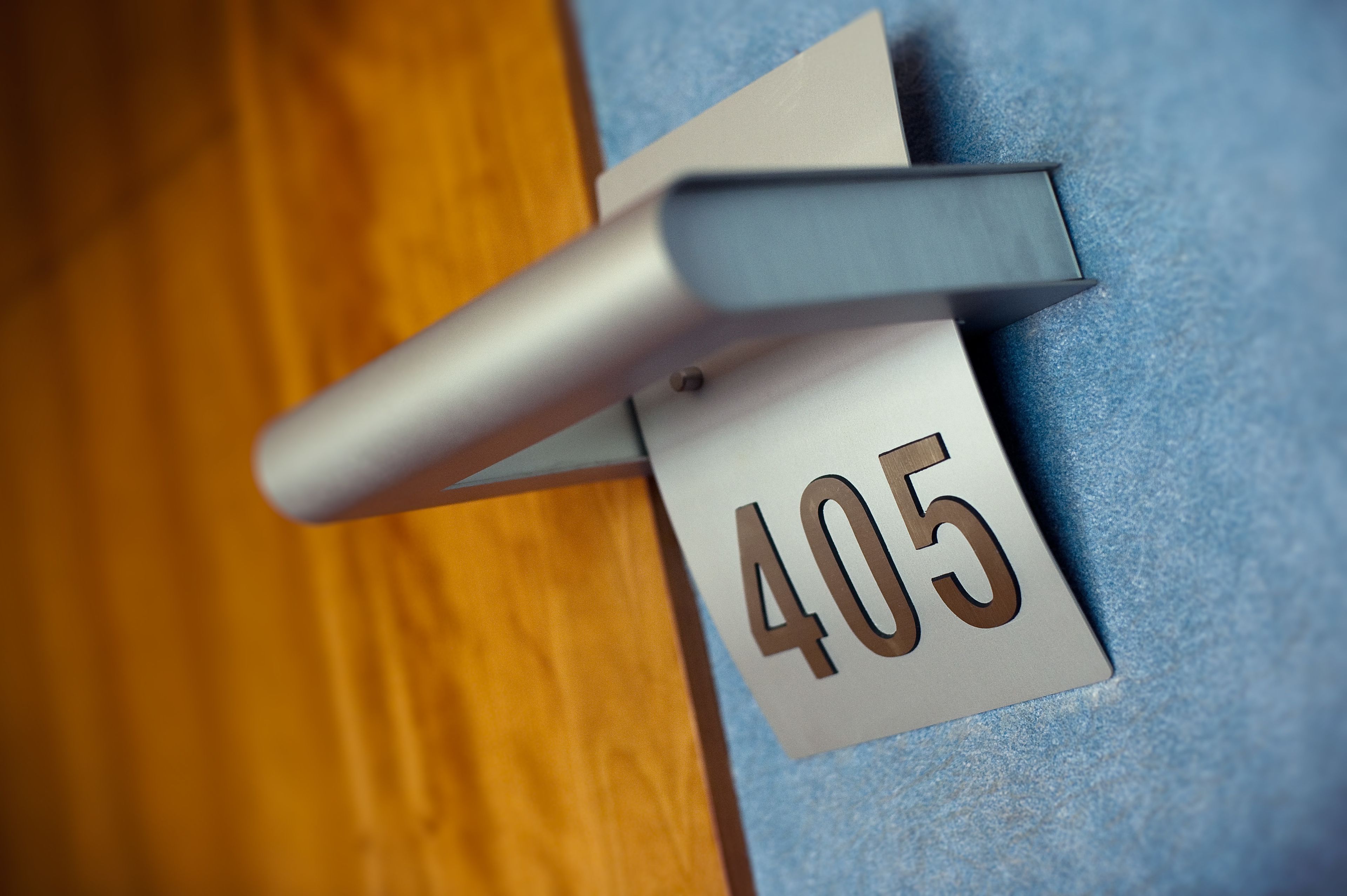 Primer plano de una puerta con un cartel con el número 405 y un picaporte metálico.