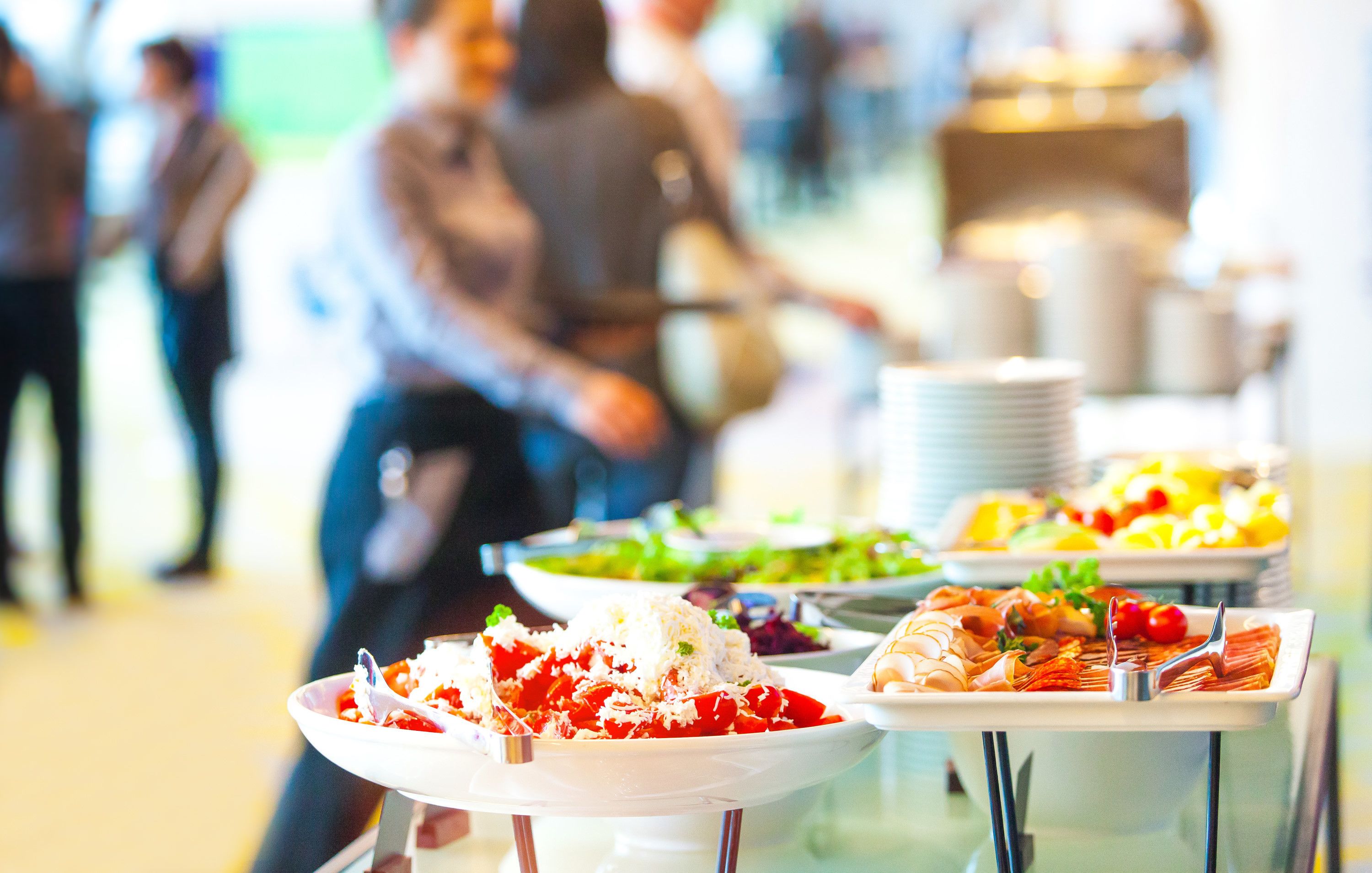 A buffet with various dishes, including pasta and salads, in a well-lit indoor setting.